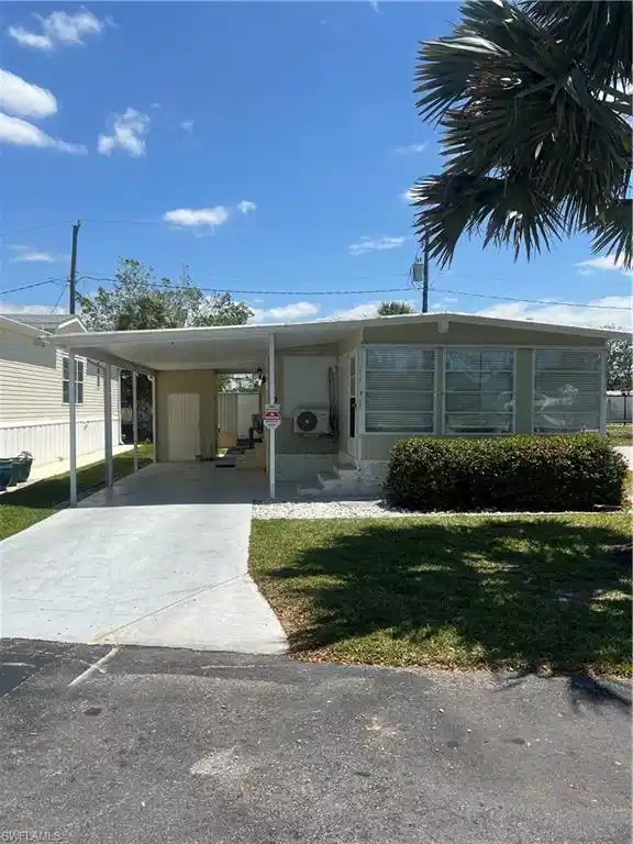 Image 1: View of front facade featuring a front yard, concrete driveway, and an attached carport