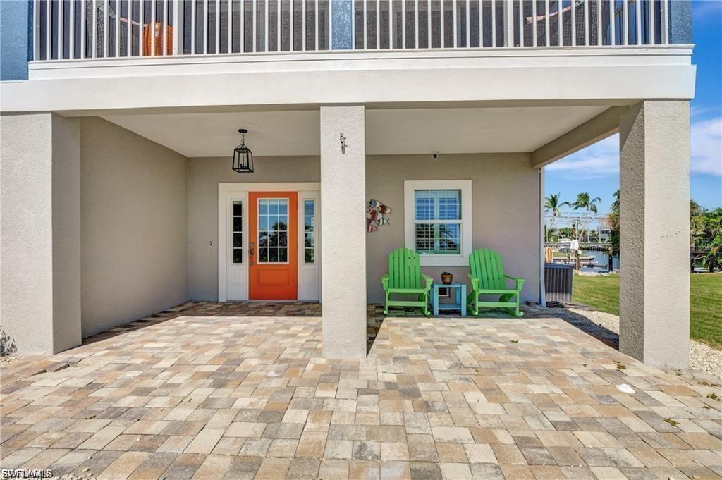Image 4: Property entrance with stucco siding, a water view, a patio area, and a carport