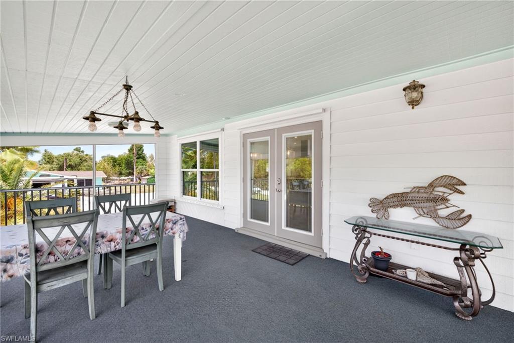 Image 4: Screen front porch has plank ceiling, dual French doors, a large picture window, and full-height railing.