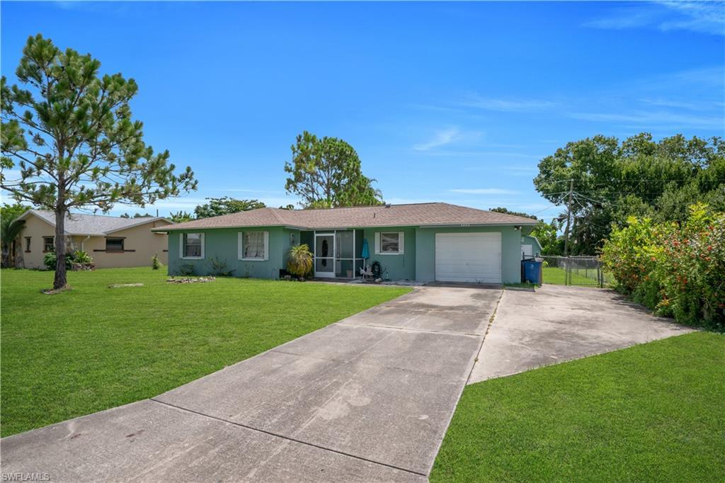 Image 2: Single-story residence featuring a light green exterior, a tan shingle roof, and a mature front lawn