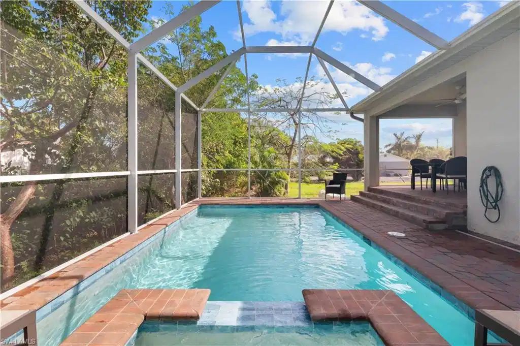 Image 1: View of swimming pool with a patio area, a pool with connected hot tub, a ceiling fan, and a lanai