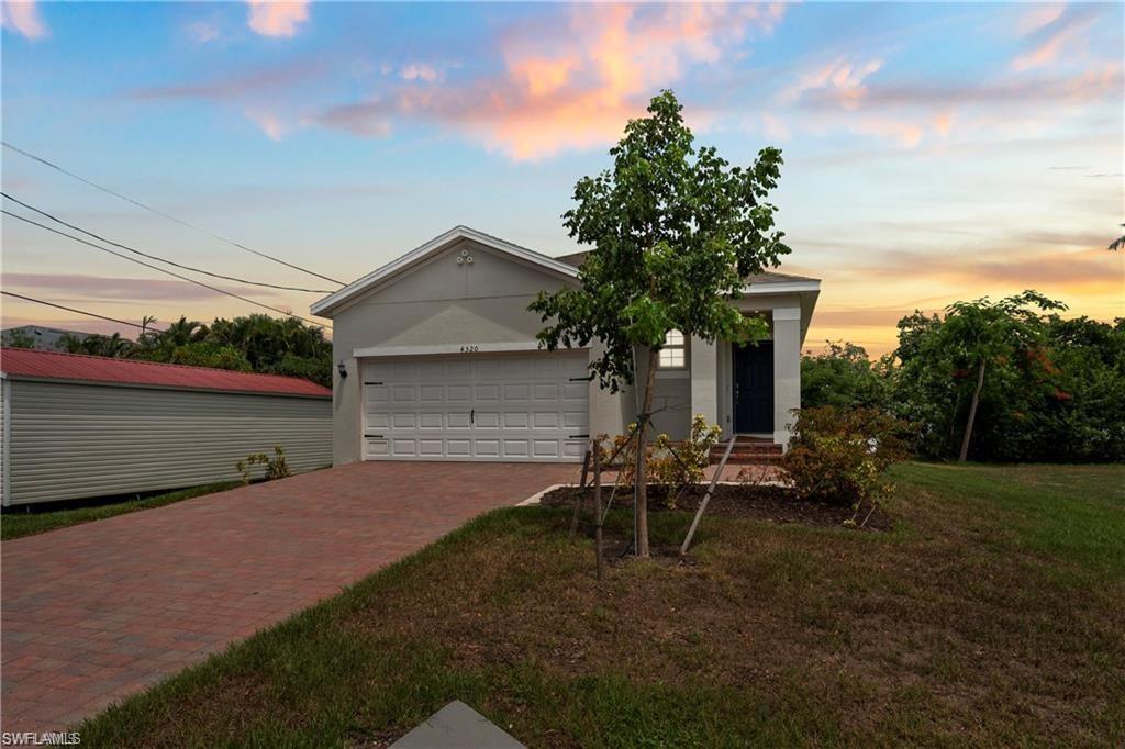 Image 2: View of front facade featuring decorative driveway, an attached garage, stucco siding, and a yard