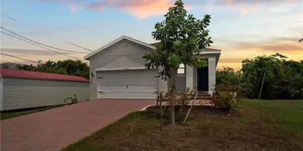 Image 2: View of front facade featuring decorative driveway, an attached garage, stucco siding, and a yard