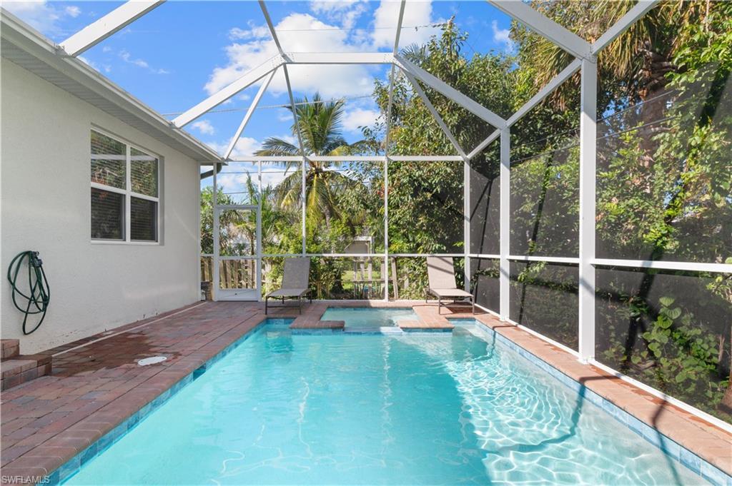 Image 3: Outdoor pool featuring an in-ground hot tub, glass enclosure, and a patio