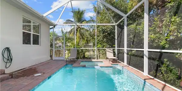 Image 3: Outdoor pool featuring an in-ground hot tub, glass enclosure, and a patio