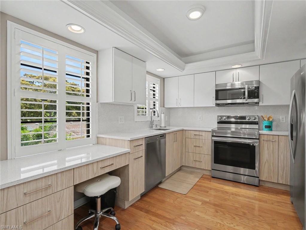 Image 2: Updated kitchen featuring two-tone cabinetry, Quartz surfaces, hardwood oak flooring, recessed lighting, and stainless steel appliances
