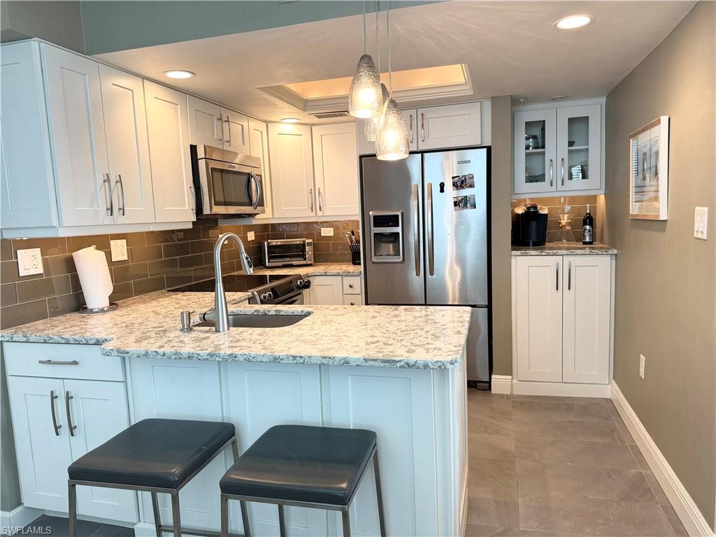 Image 2: Kitchen with tasteful backsplash, appliances with stainless steel finishes, white cabinets, glass insert cabinets, and an eat in Kitchen