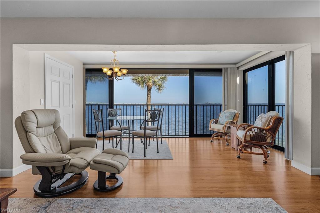 Image 3: Living area featuring a notable chandelier, wood-type flooring, and a water view