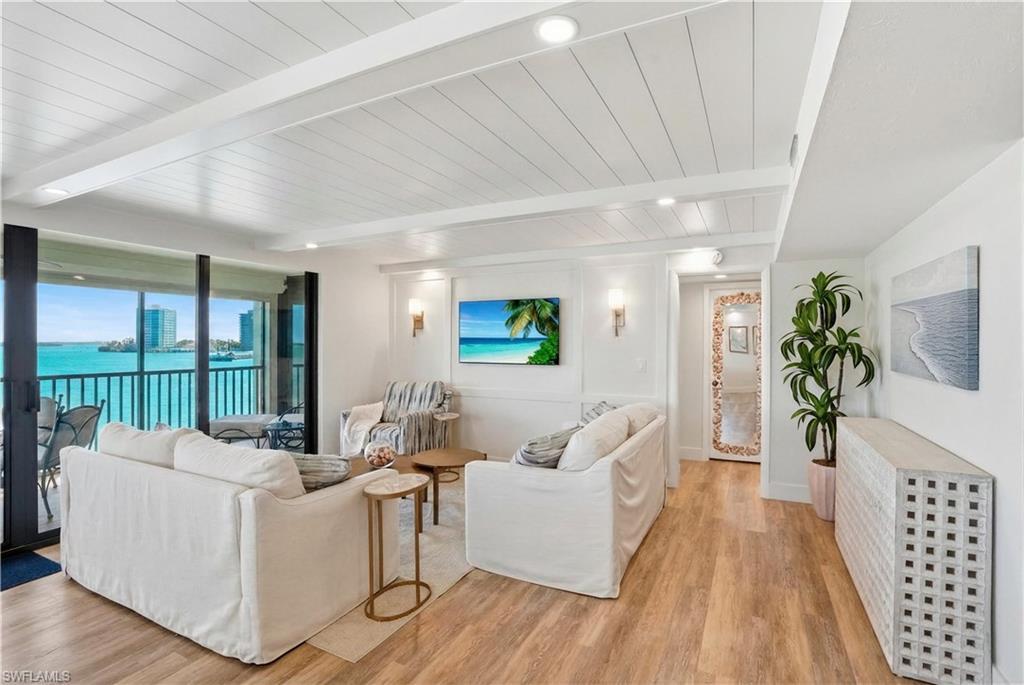 Image 4: Living area with wood-finish flooring, shiplap ceiling, recessed lighting, and wall sconces - Virtually Edited Image
