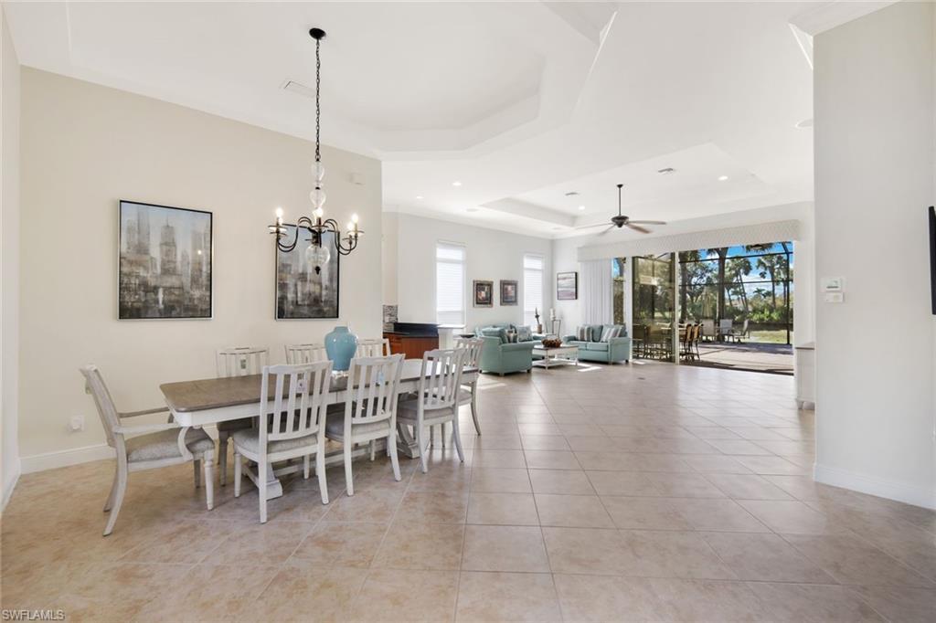 Image 2: Dining area featuring a tray ceiling, light tile patterned flooring, a chandelier, ceiling fan, and recessed lighting