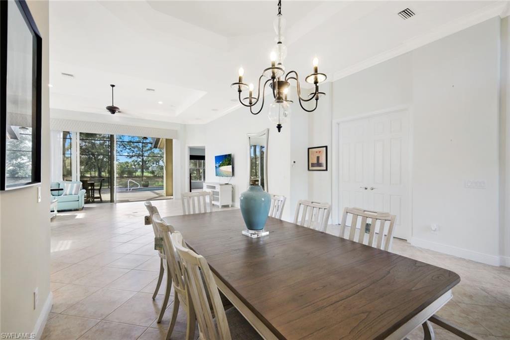 Image 3: Dining space featuring a chandelier, a tray ceiling, light tile patterned floors, a ceiling fan, and ornamental molding