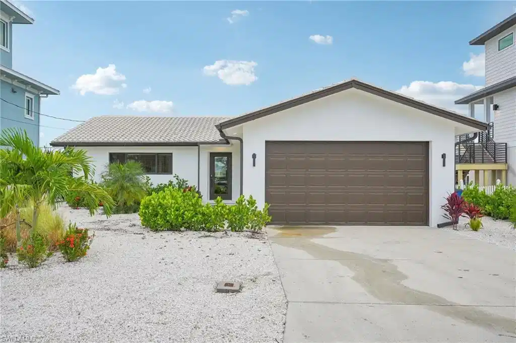 Image 1: View of front facade featuring stucco siding, driveway, and a garage