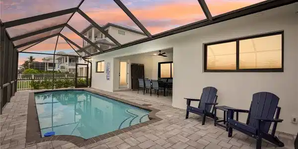 Image 2: Pool at dusk with a sunroom, a lanai, a ceiling fan, and a patio