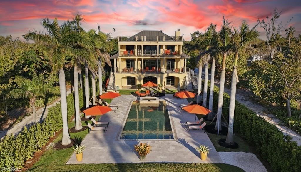 Image 2: Back of property featuring a balcony, a patio area, and a swimming pool