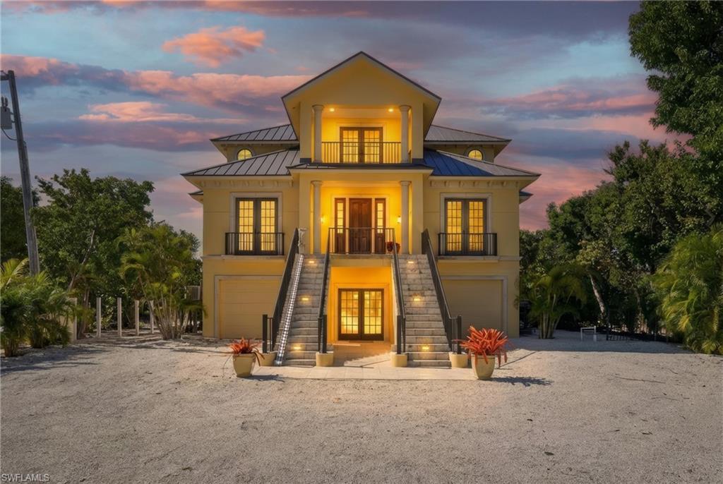 Image 4: Back of property featuring french doors, a standing seam roof, an attached garage, and driveway