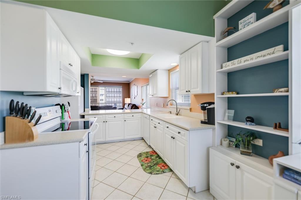 Image 4: Kitchen with white appliances, open shelves, white cabinetry, and light tile patterned floors