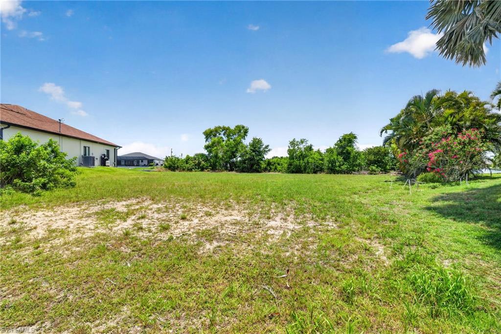 Image 2: Expansive grass and sand lot with mature trees framing the perimeter