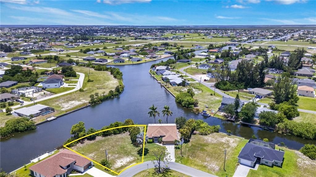 Image 3: Canal-front property featuring a single-story residence with a tan exterior and a paved driveway