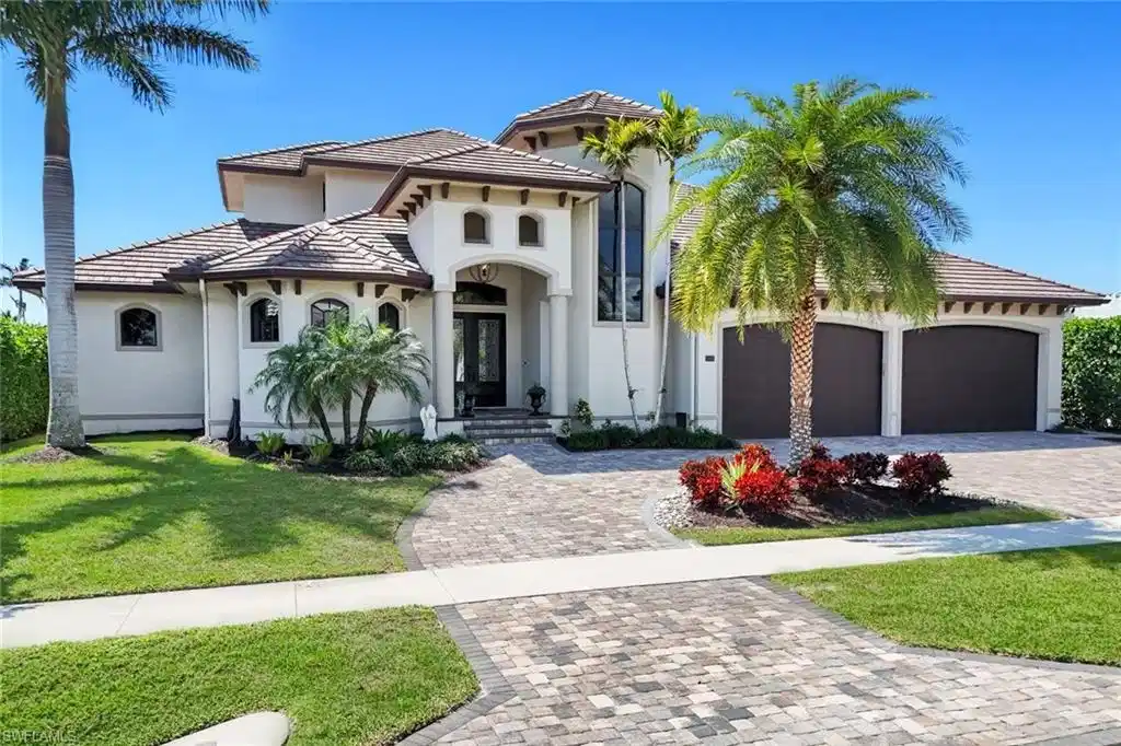 Image 1: Mediterranean / spanish-style home with decorative driveway, a front yard, stucco siding, a tiled roof, and a garage