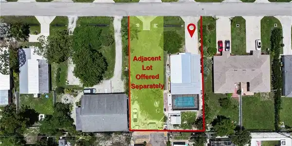 Image 2: Aerial view of a residential property featuring a rectangular swimming pool, a screened enclosure, and a paved driveway