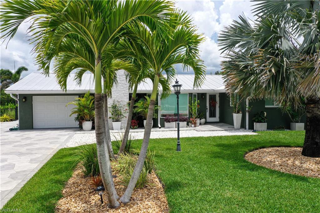 Image 2: View of grassy yard with a garage and driveway