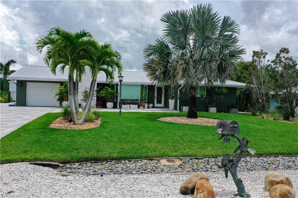 Image 3: Ranch-style house with a front yard, a garage, driveway, a metal roof, and stucco siding