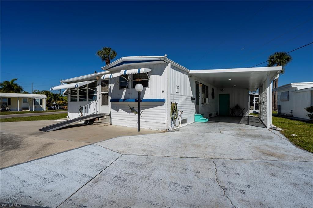 Image 3: View of front of property featuring driveway, an attached carport, and entry steps