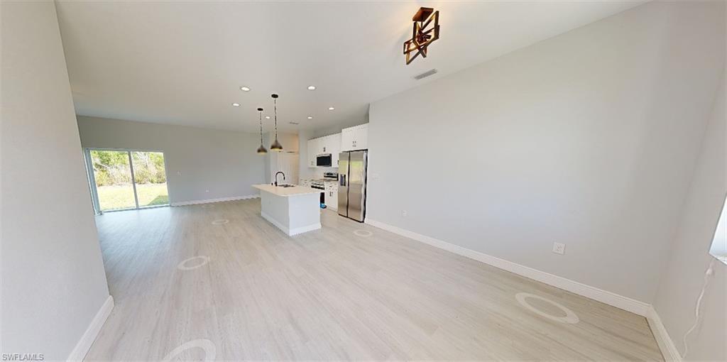 Image 4: Kitchen featuring open floor plan, white cabinetry, an island with sink, stainless steel appliances, and light wood-style floors