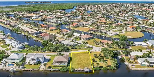 Image 2: Aerial view of residential area with a large body of water and property parcel outlined
