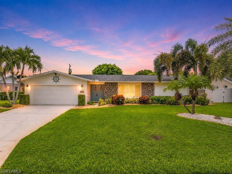 Image 3: Single-story residence featuring a two-car garage, stone facade accents, and a vibrant green lawn