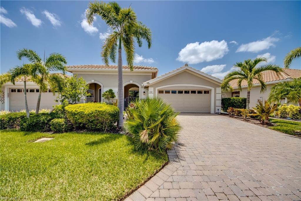 Image 2: Property exterior featuring a paver driveway, lush green lawn, mature palm trees, and manicured shrubbery