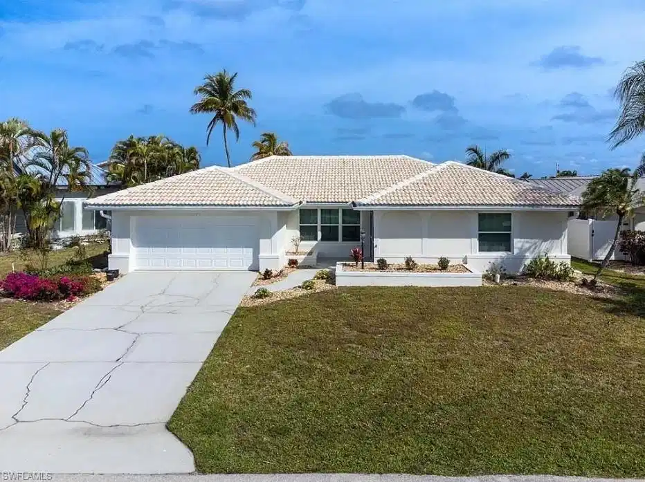 Image 1: Single-story residence featuring a white exterior, a white tile roof, and a two-car garage