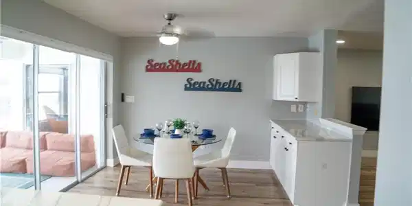 Image 2: Sliding glass doors opening to an outdoor area with seating, wood-finish flooring, a ceiling fan with light fixture, and white cabinetry with a light-toned countertop