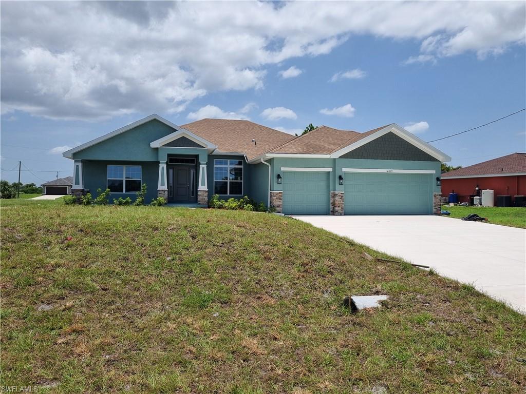 Image 1: View of front of home with a garage, driveway, a front yard, and stone siding