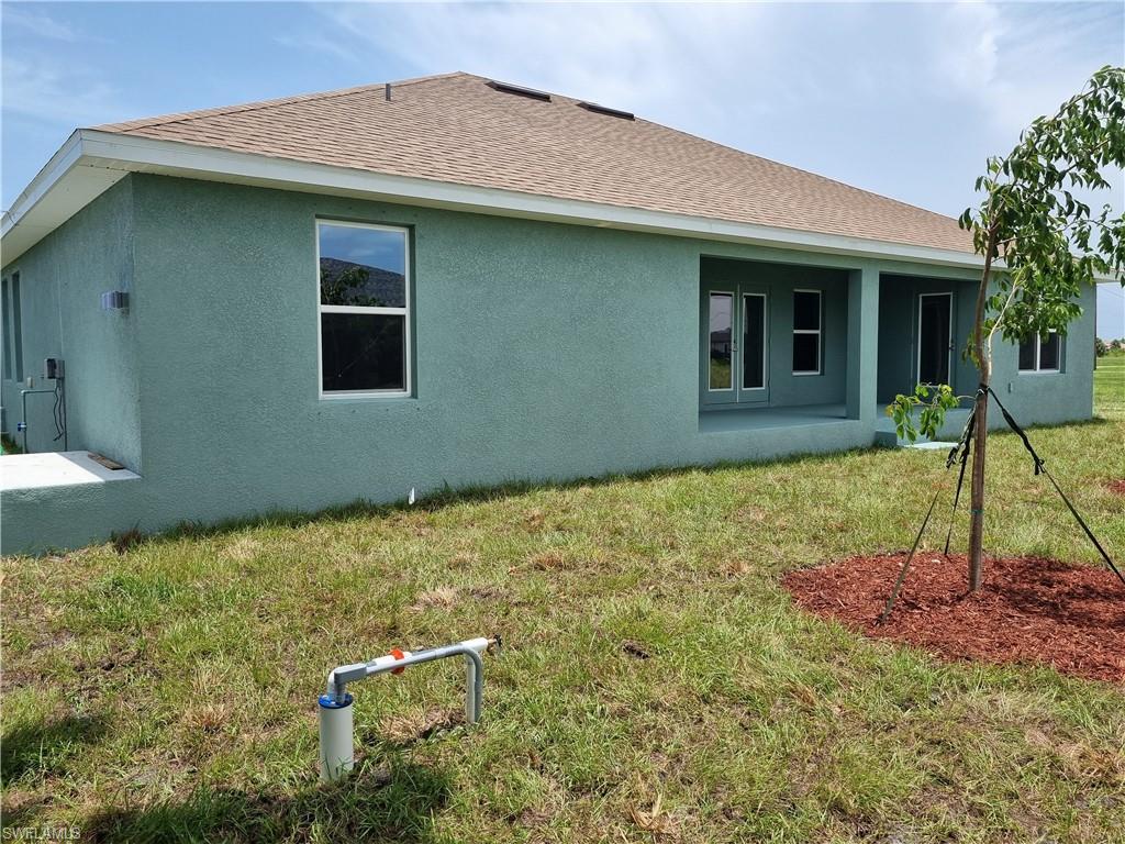 Image 3: Rear view of property featuring stucco siding, a yard, and roof with shingles