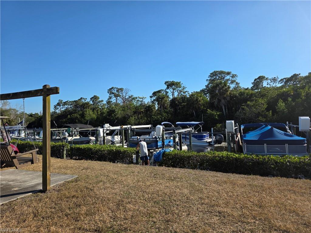 Image 3: View of grassy yard with view of wooded area and a dock