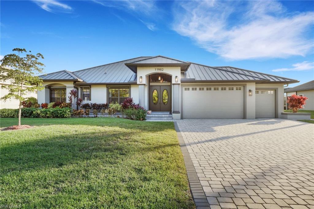 Image 2: View of front facade with a standing seam roof, a metal roof, decorative driveway, and a front lawn