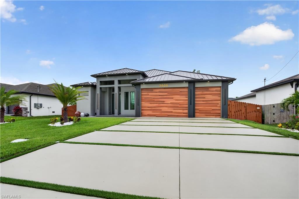 Image 3: Contemporary exterior featuring a dark metal roof, wood-finish garage doors, and a segmented concrete driveway