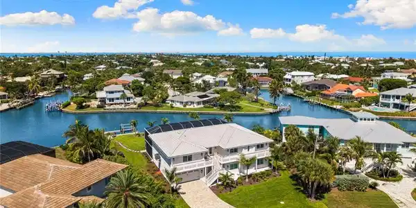 Image 2: Waterfront property featuring a private boat dock, lush tropical landscaping, and a paver driveway