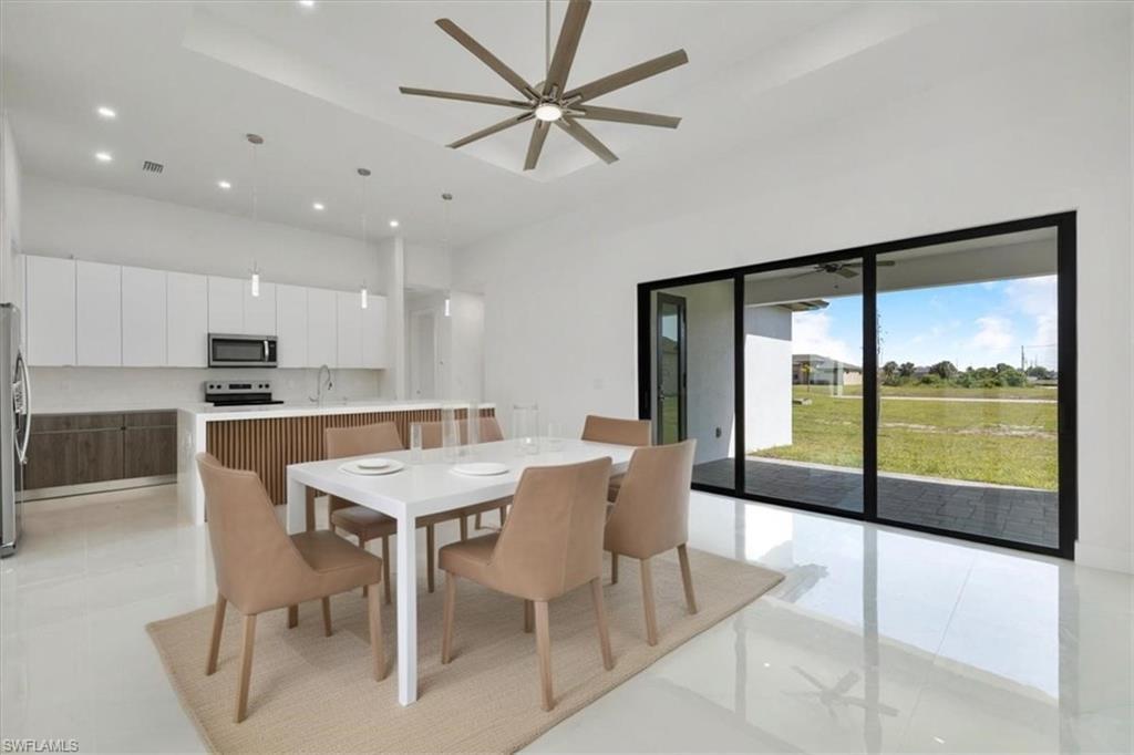 Image 2: Kitchen featuring open floor plan, white cabinetry, stainless steel appliances, a raised ceiling, and modern cabinets