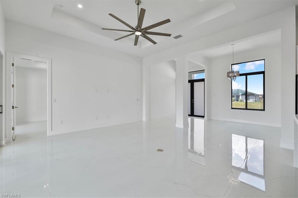 Image 4: Living room with marble finish floor, a tray ceiling, a high ceiling, and a ceiling fan
