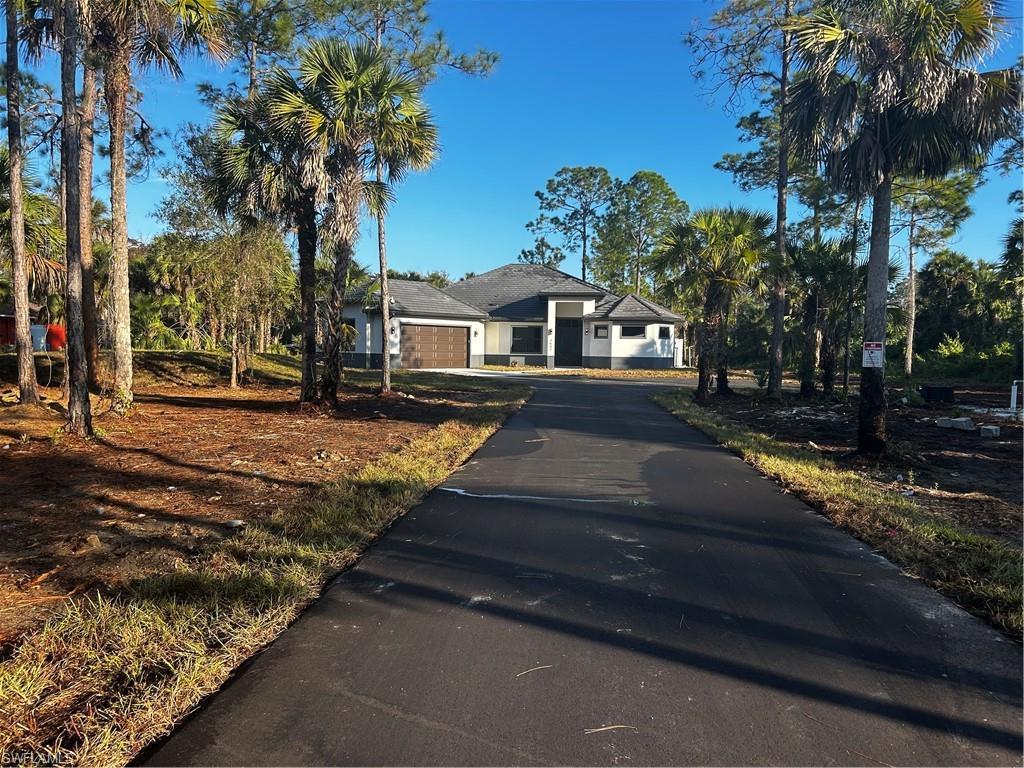 Image 1: View of front facade featuring asphalt driveway and a garage