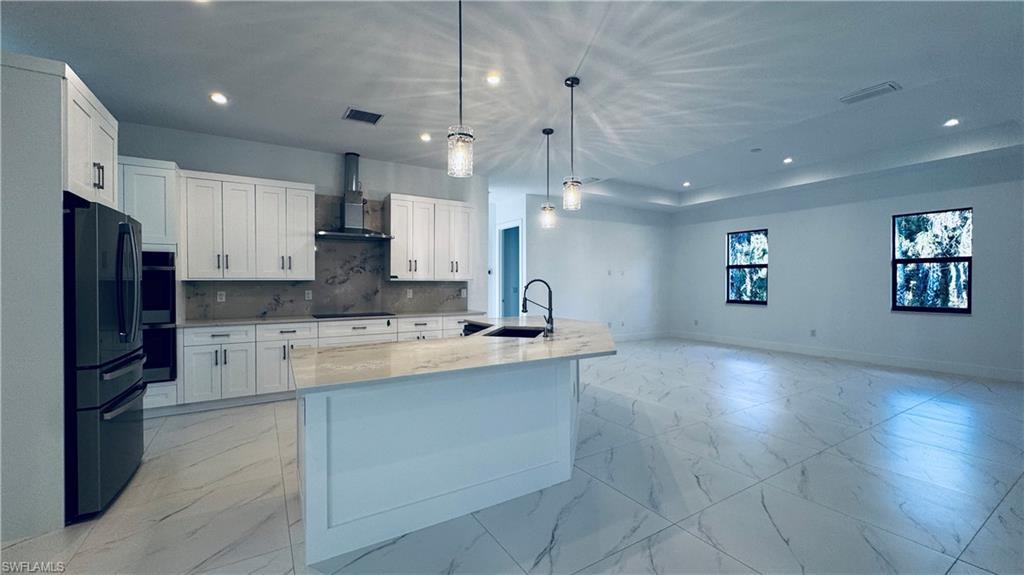 Image 3: Kitchen with light marble finish flooring, white cabinetry, black appliances, and recessed lighting