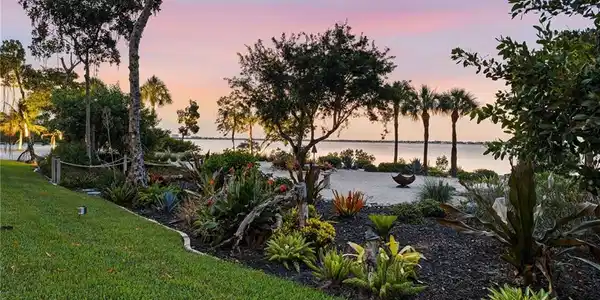 Image 4: This exceptional residence is surrounded by lush, beautifully manicured green space, creating a private and serene setting between the home and its exquisitely landscaped private beach.