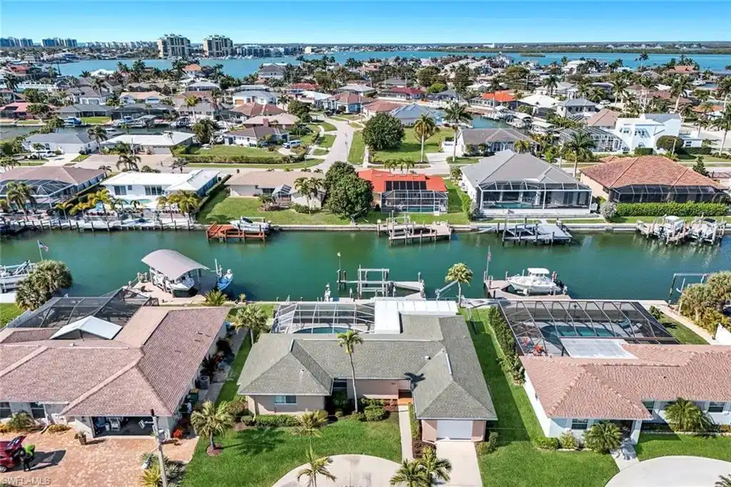 Image 1: Aerial perspective of suburban area featuring a nearby body of water