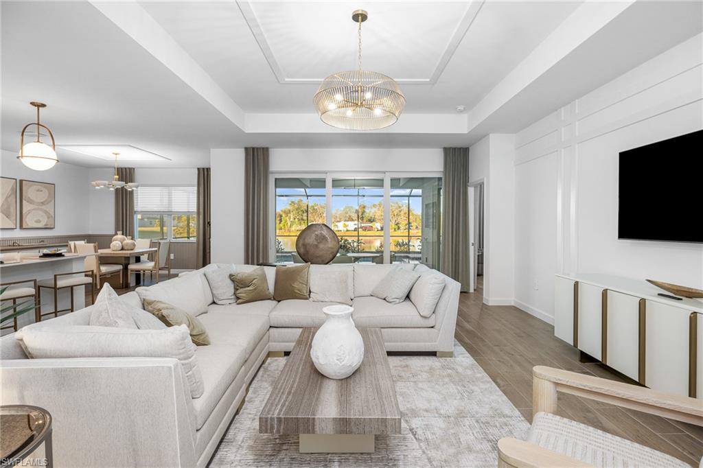 Image 3: Living area featuring a chandelier, a raised ceiling, and plenty of natural light