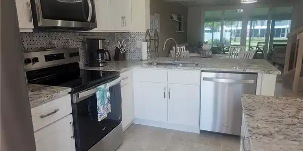 Image 4: Kitchen featuring stainless steel appliances, backsplash, a peninsula, white cabinets, and light stone counters