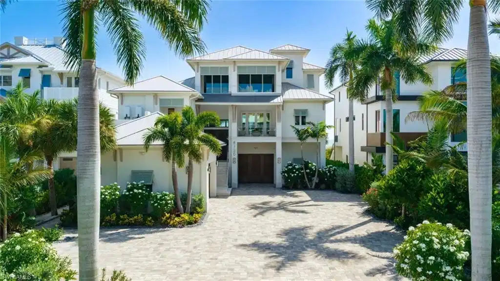 Image 1: Contemporary coastal residence featuring a two-story design with stucco exterior, metal railings, and expansive glass panels - Virtually Edited Image