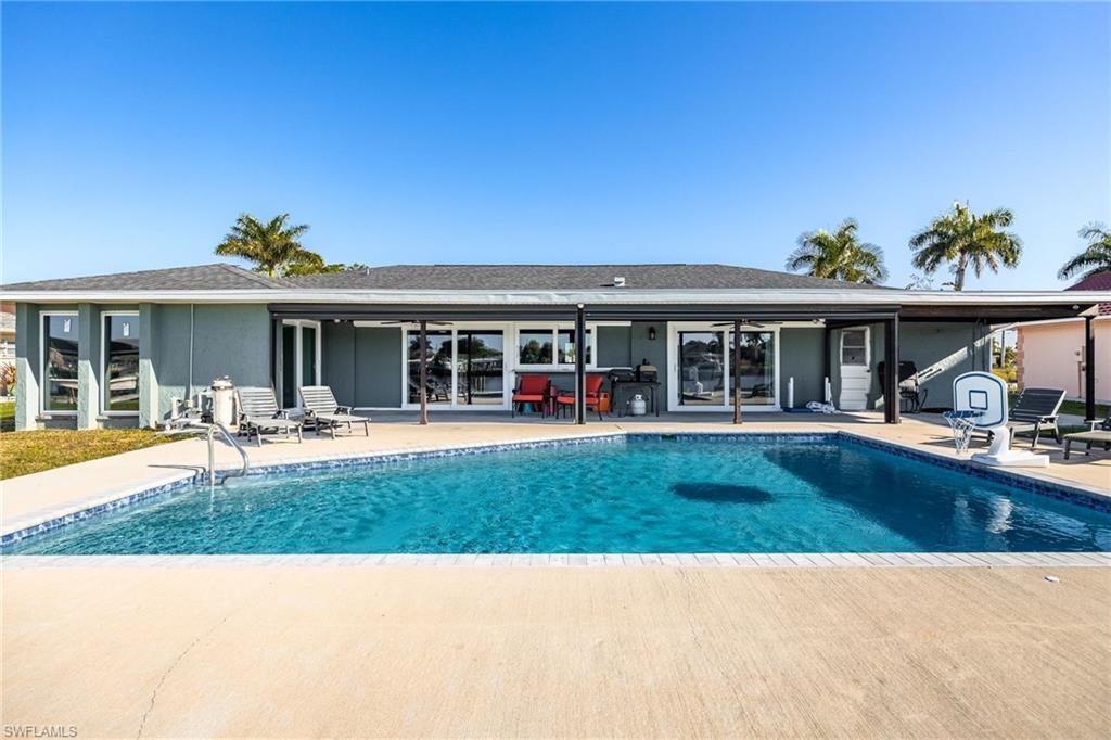 Image 4: Rear view of house with a patio, an outdoor pool, and roof with shingles