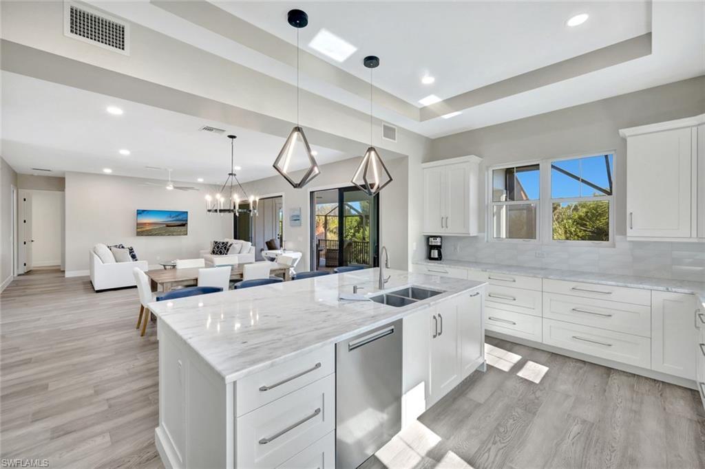 Image 1: Kitchen featuring white cabinets, light stone counters, open floor plan, dishwasher, and pendant lighting